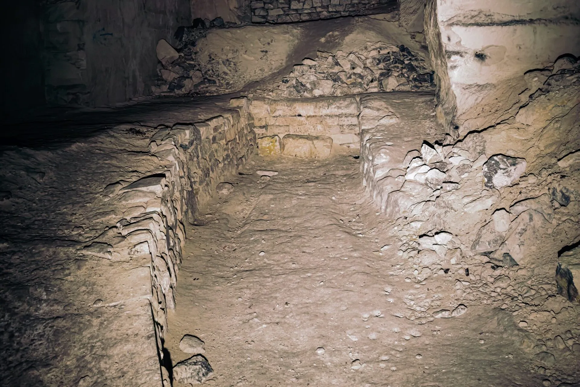 A worked-out chamber with waste stone stacked into drystone walls along both sides of the floor